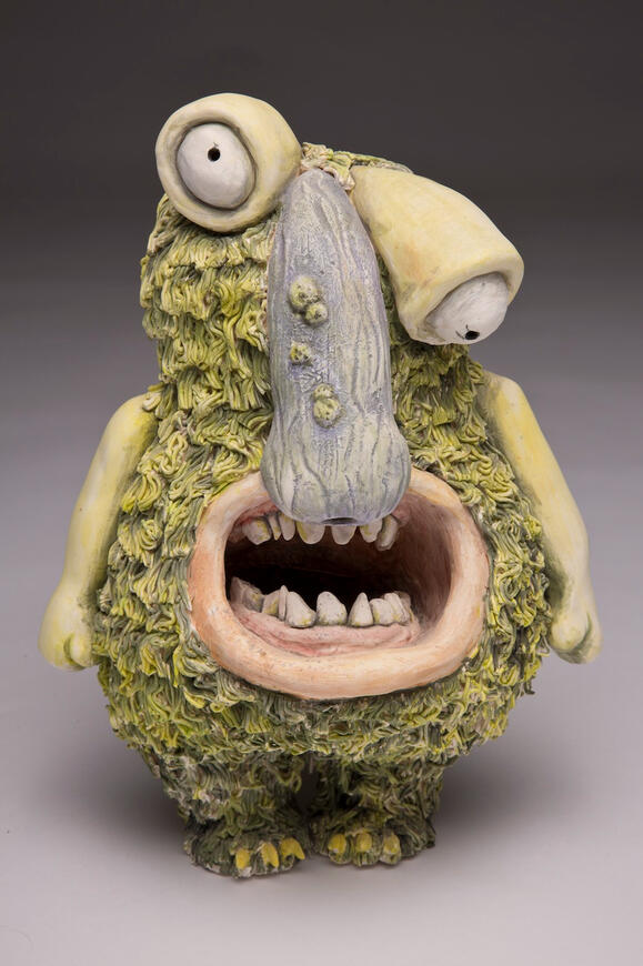 Ceramic green monster with mouth open and a large nose.